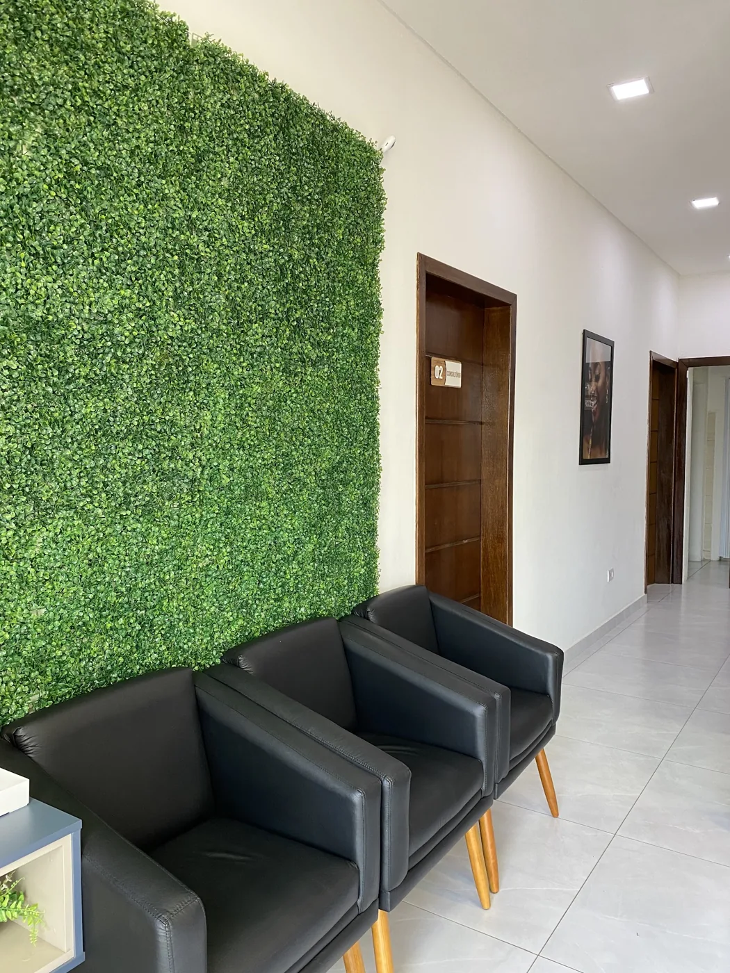 Poltronas da área de espera com parede verde e acesso aos consultórios